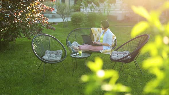 Freelance Woman Works on Laptop at Home in the Backyard