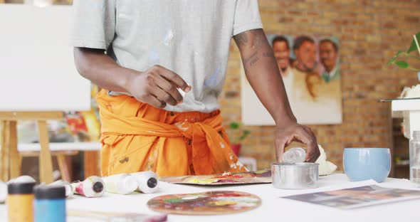 Midsection of african american male painter mixing paint in artist studio