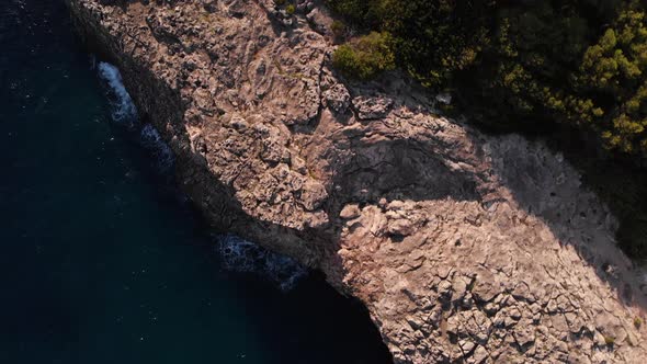 AERIAL: Looking down to fissured coast in spain next to pool houses