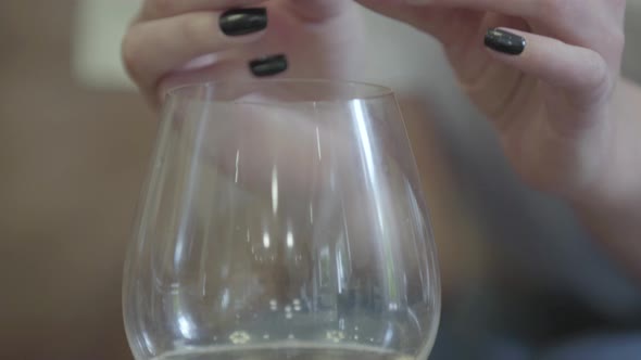 Female Hands Holding Golden Wedding Ring Under the Glass of White Wine