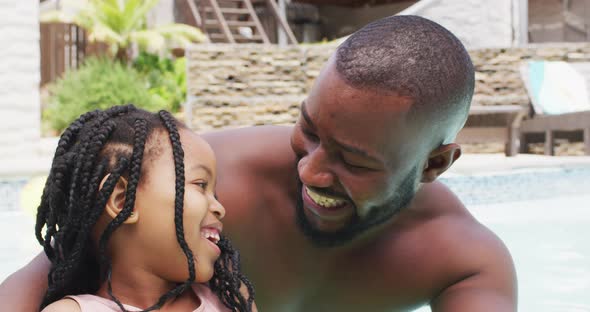 Portrait of happy african american father and daughter having fun in swimming pool