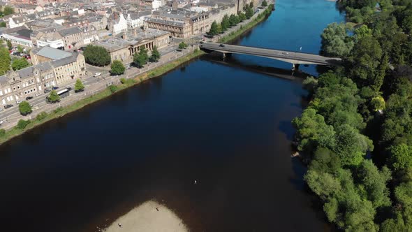 Aerial footage above River Tay tilting up revealing beautiful City of Perth with mountains in the ba