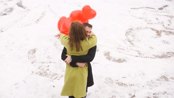 Happy Young Couple with Red Balloons Hugging and Enjoying Time Together