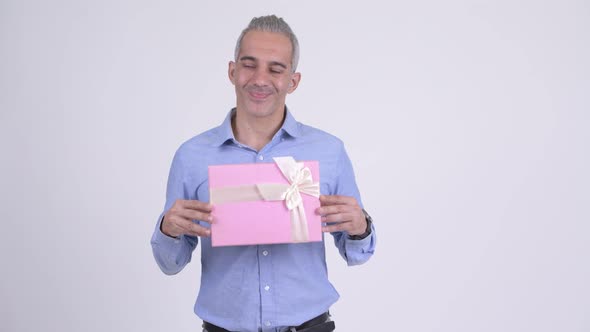 Happy Persian Businessman Thinking While Holding Gift Box