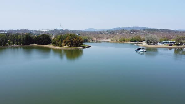 Flying towards Canberra's Parliament House as a tourist boat cruises on the lake.