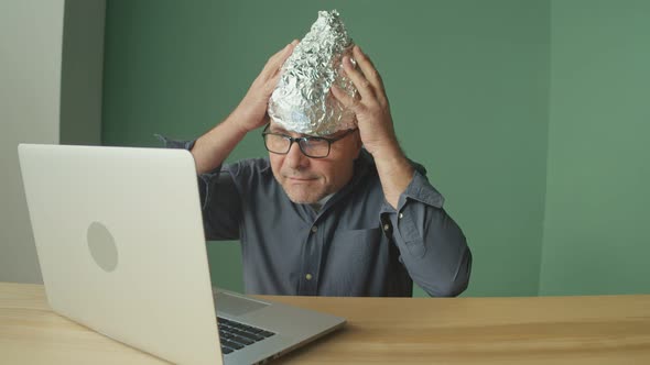 Paranoid Man Working on a Laptop Calming Down Takes Off His Foil Cap