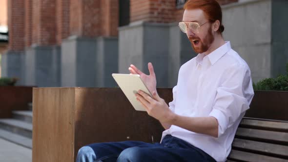 Excited Man Celebrating Success on Tablet Sitting on Bench