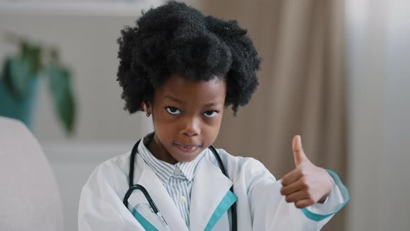 Closeup Little Cute Kid Girl in Medical Gown Looking at Camera Posing Indoors Smiling Pretending Be