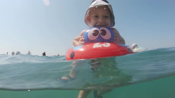 Little Boy Swimming and Playing at Sea with Rubber Ring. Small Kid Enjoying Swimming in Sea with