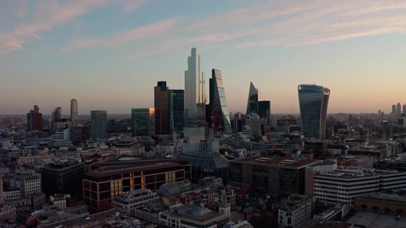 Cinematic circling drone shot of City of London skyscrapers at sunrise
