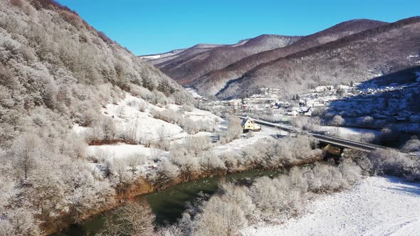 Mountain Winter Road That Crosses the River Aerial View