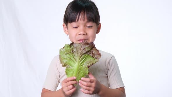 appy little girl with fresh salad with showing thumbs up on white background in studio.