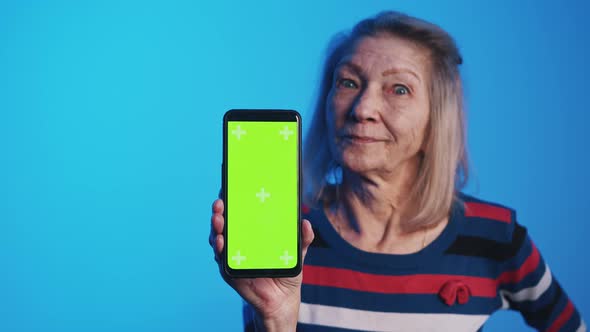 Old Woman with Wide Opened Eyes Holding Smartphone with Green Screen