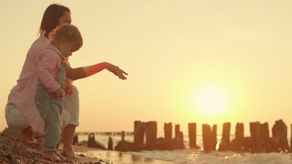 Mother and Daughter Throw Stones Into the Sea