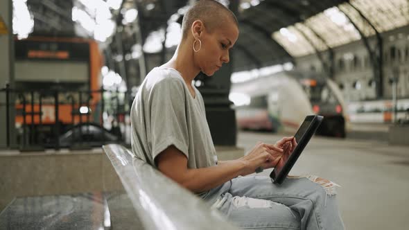 Handsome bald woman wearing t-shirt texting by tablet