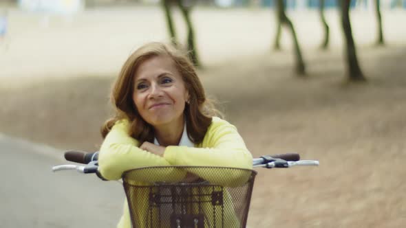 Smiling Woman Leaning Against Handlebars of Bike