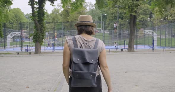 Woman Walking with His Back in Park, Background Urban Sports Field Basketball Court