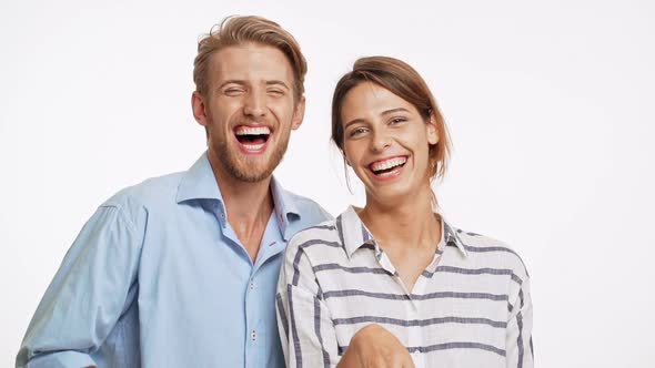 Funny Caucasian Couple Looking at Camera and Laughing in Slowmotion on White Background