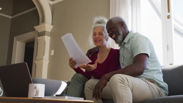 Mixed race senior couple discussing finances together in the living room at home