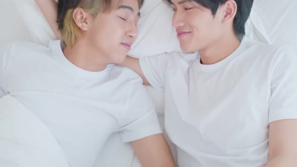 Asian young male gay family lying down on bed and look at each other.