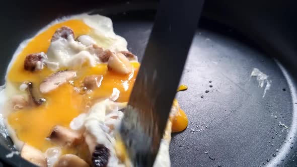 Cooking breakfast in a pan. Homemade food. Eggs are cooked in a frying pan with mushrooms and season