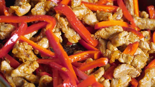 Sliced pieces of vegetables, onions, sweet peppers and meat are fried in oil