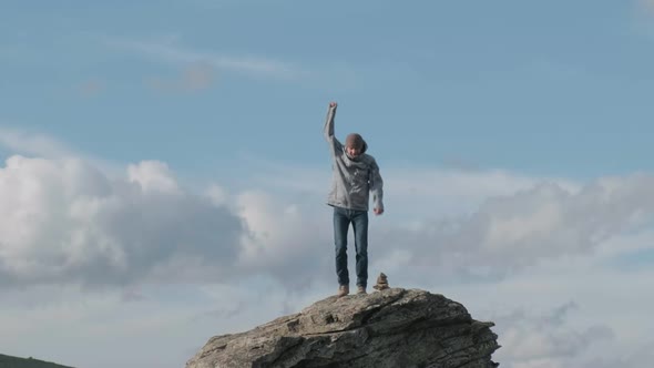 Funny Man Jumping on Top Cliff Celebrates Climbing to Mountain on Sunny Day