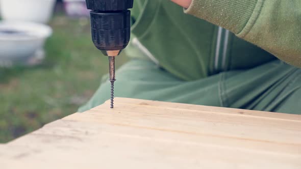 Man Screwing Screw in Wooden Plank