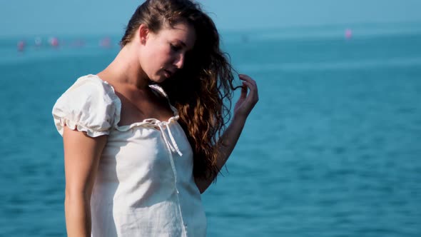 girl in a white sundress on the background of the sea on a bright sunny day