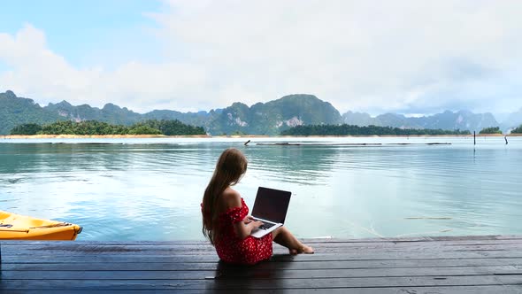 Travel Woman Sitting on Wooden Pier Using Laptop Typing Remote Chatting