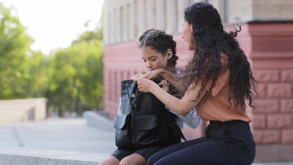 Caring Mother Hispanic Woman Mommy Parent Sits Outdoors with Beloved Daughter Schoolgirl Helps