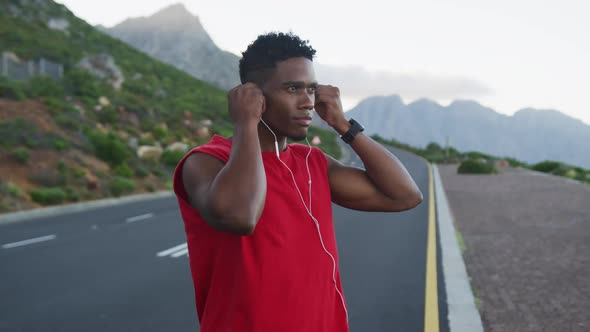 African american man wearing earphones while standing on the road