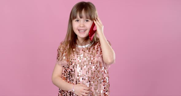 Cheerful Little Blonde Kid Girl 6-7 Years Old in Sequin Dress Talking on Mobile Phone