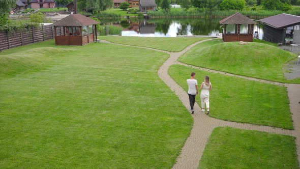 Extreme Wide Shot Summer Ecoresort Outdoors with Cheerful Young Couple Having Fun Walking to Pond