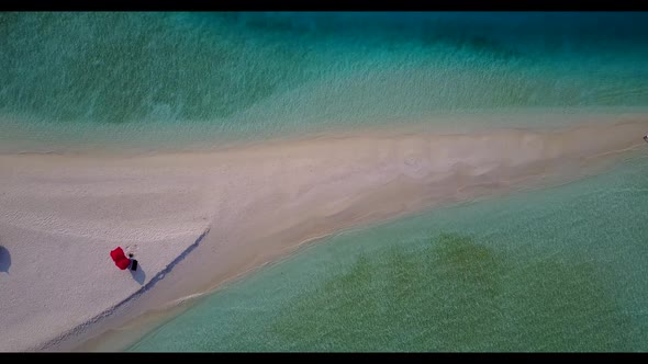 Aerial flying over sky of tranquil coastline beach voyage by blue water with white sand background o