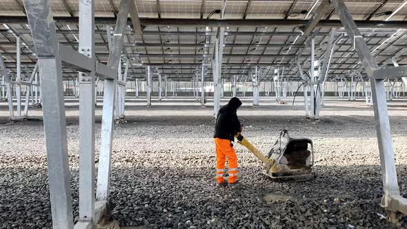 An Employee Using a Vibrating Machine Compresses the Rubble on the Future Parking Lot Under the