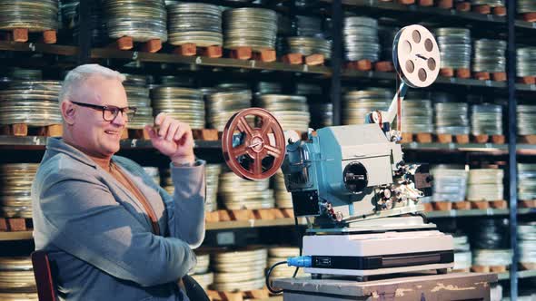 Archive Specialist is Laughing Next to the Antique Film Projector