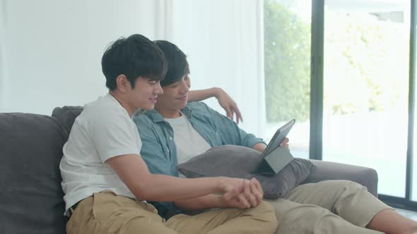 Young Gay couple using tablet at home.