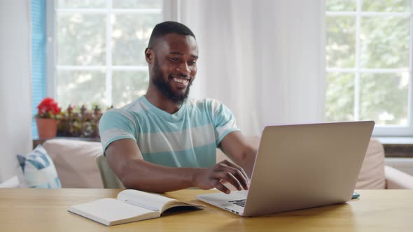 Cheerful Afro Guy Working on Laptop From Home Office