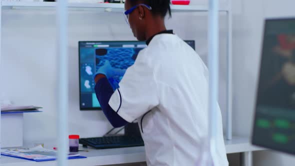 African Chemist Nurse Writing on Computer Analysis Results