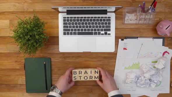 Phrase Brainstorm is Composed of Wooden Cubes on Office Table with Hands