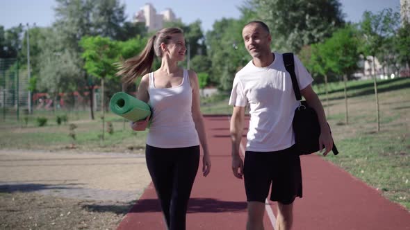 Portrait of Cheerful Caucasian Couple Strolling on Running Track After Morning Training. Happy Man