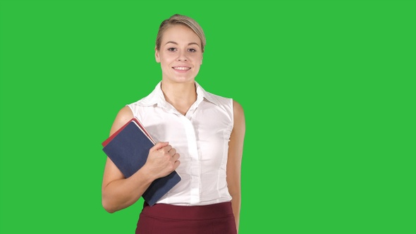 Beautiful young woman with notebooks walking on a Green