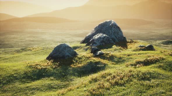 Meadow with Huge Stones Among the Grass on the Hillside at Sunset