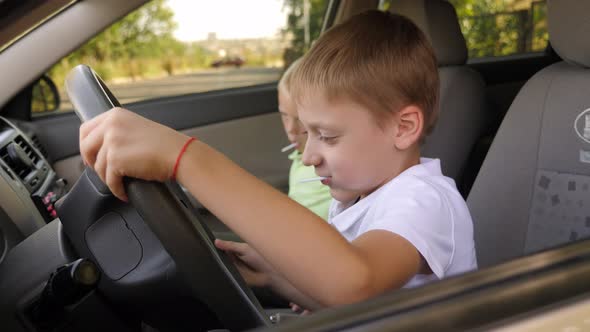 Two Boys with Lollipops are Playing in the Car They Turn the Steering Wheel