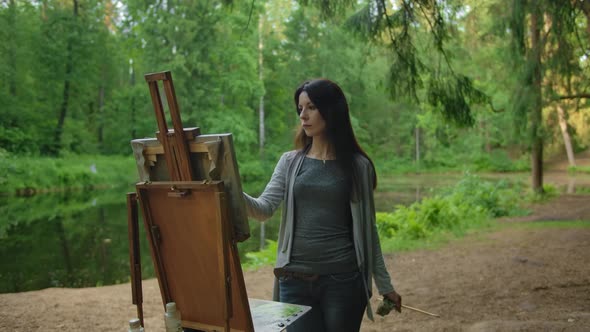 Beautiful Woman Artist Paints a Landscape in a Park Near a Pond