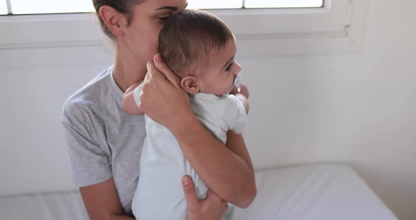 Young loving mom holding her baby at home inside bedroom