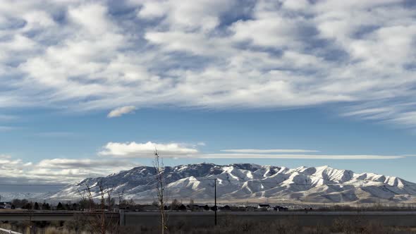 A busy highway in the foreground with a snowy mountain in the background and cloudscape overhead - p