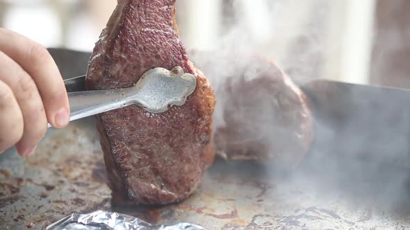 Cooking beef steaks on the stove with tongs