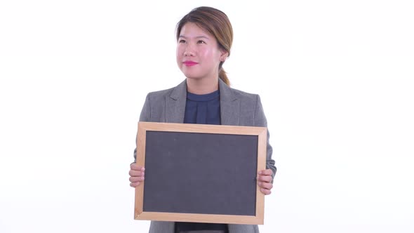 Happy Young Asian Businesswoman Thinking While Holding Blackboard
